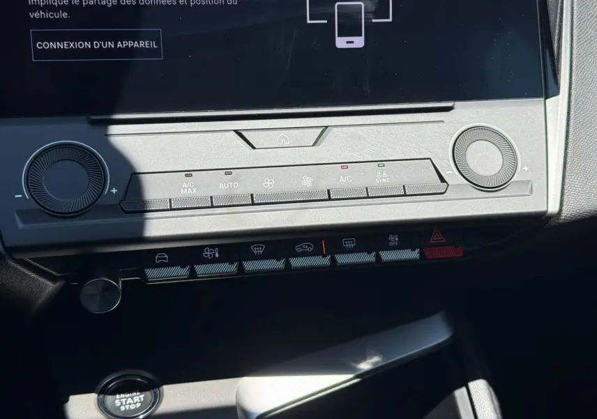 Vue rapprochée de la console centrale de la Peugeot e-308 2025 noire, montrant les commandes climatisation et bouton start/stop.