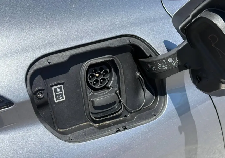 Prise de recharge électrique ouverte côté gauche sur Peugeot e-308 2025 noir Perla Nera, détail du port de charge.