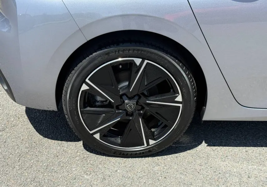 Gros plan sur la roue arrière droite d'une Peugeot 308 e-308 noire avec jante alu noire et argentée au design moderne.
