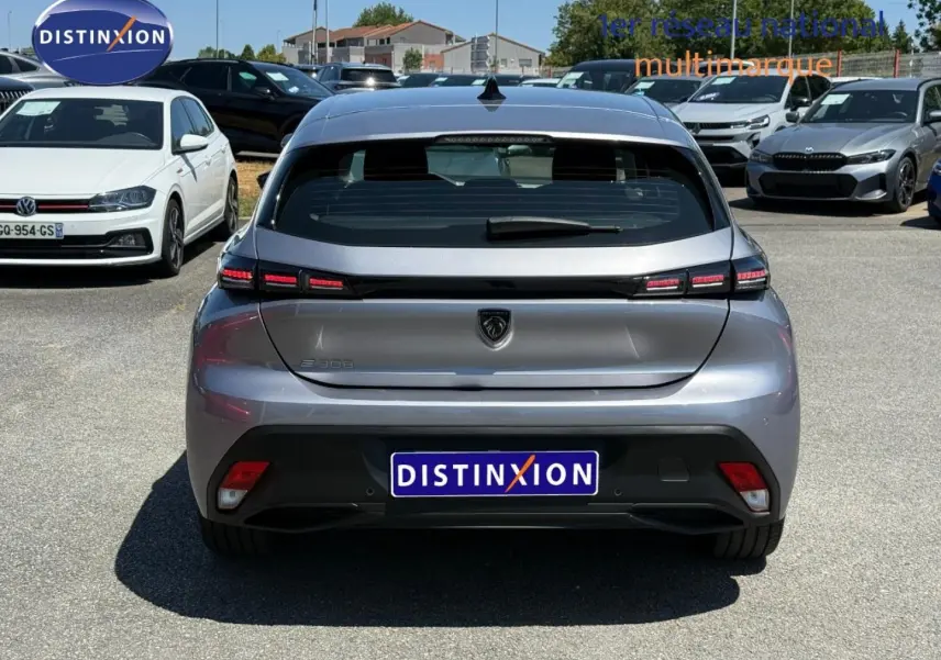 Vue arrière d'une Peugeot e-308 2025 gris métallisé, avec feux arrière LED et logo lion central.