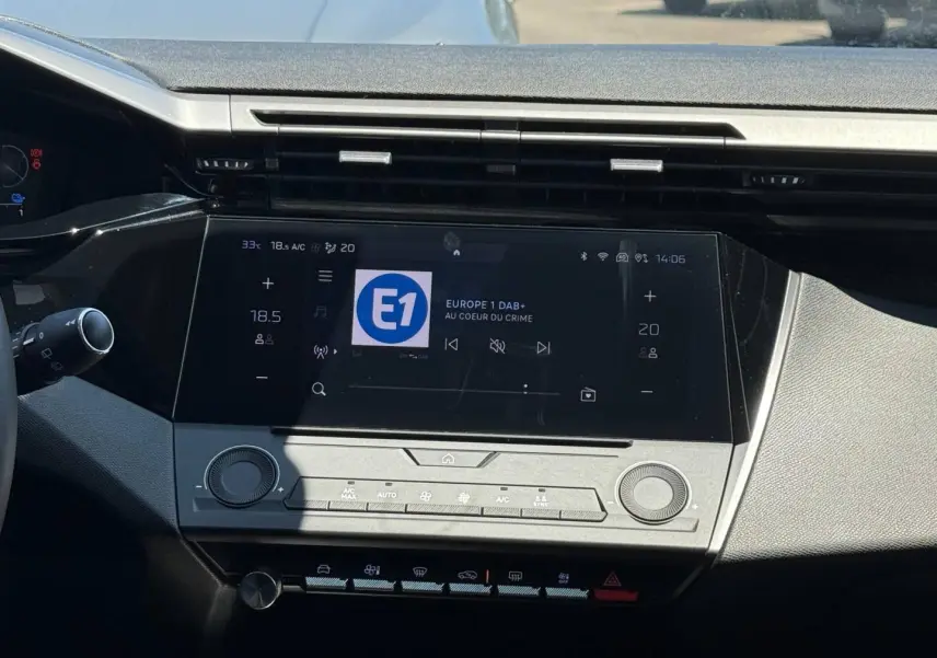Vue rapprochée de la console centrale tactile de la Peugeot e-308 2025, affichant l’écran multimédia et commandes clim.
