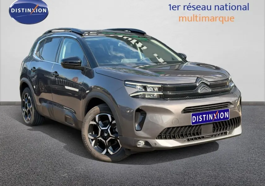 Citroën C5 Aircross gris Platinium en 3/4 avant droit avec jantes alliage et barres de toit visibles.