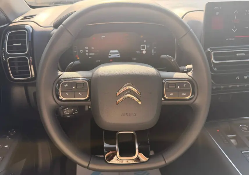 Vue rapprochée du volant cuir multifonction noir du Citroën C5 Aircross 2025 avec tableau de bord digital en arrière-plan.