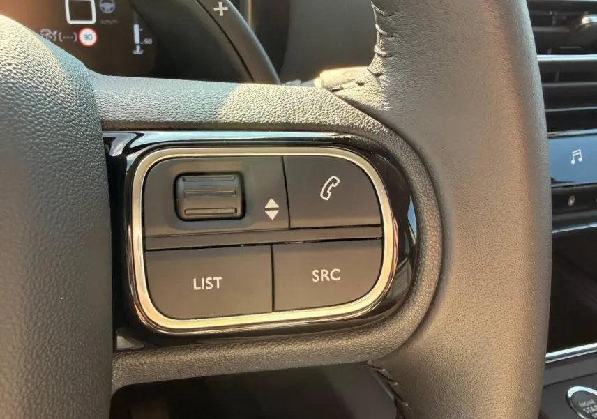Gros plan sur les commandes multifonctions gauche du volant cuir du Citroën C5 Aircross gris Platinium 2025.