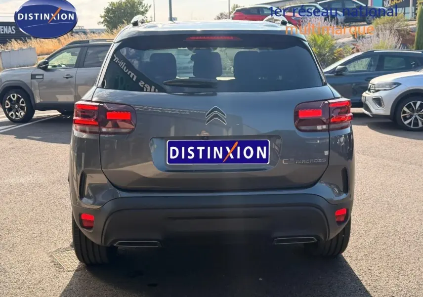 Vue arrière d'un Citroën C5 Aircross gris Platinium avec feux arrière LED et barres de toit visibles.