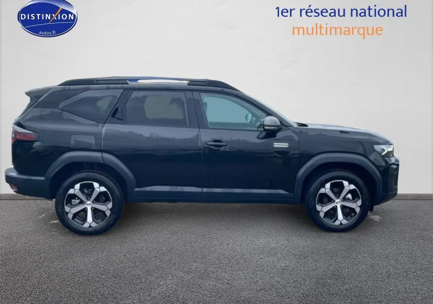 Vue latérale droite du SUV Dacia Bigster noir 2025 avec jantes alliage diamantées et barres de toit visibles.