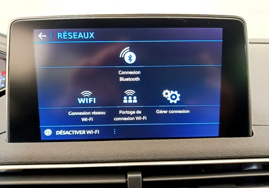 Écran tactile central affichant les options réseau Bluetooth et Wi-Fi dans le tableau de bord du Peugeot 3008 gris foncé.