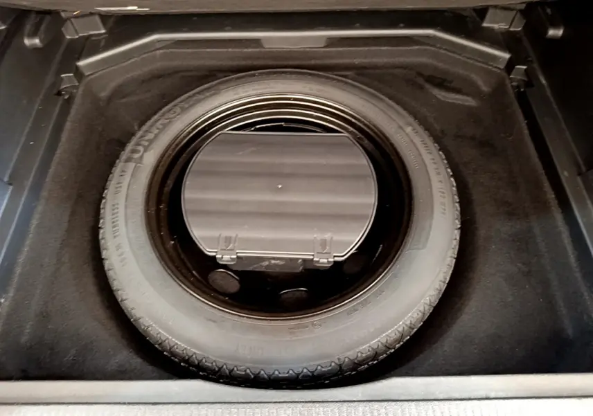 Vue plongeante sur la roue de secours dans le coffre d’un Peugeot 3008 gris foncé de 2020.