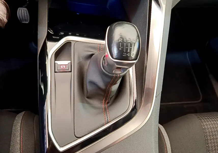 Gros plan sur le levier de vitesses manuel noir avec surpiqûres rouges du Peugeot 3008 gris foncé, console centrale visible.