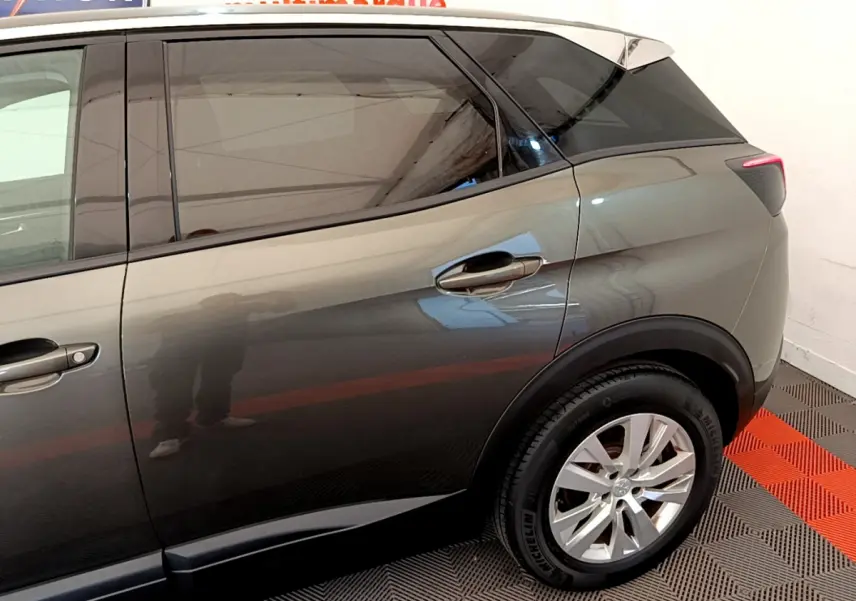Vue latérale côté droit du Peugeot 3008 gris foncé, mettant en valeur la porte arrière et la roue arrière.