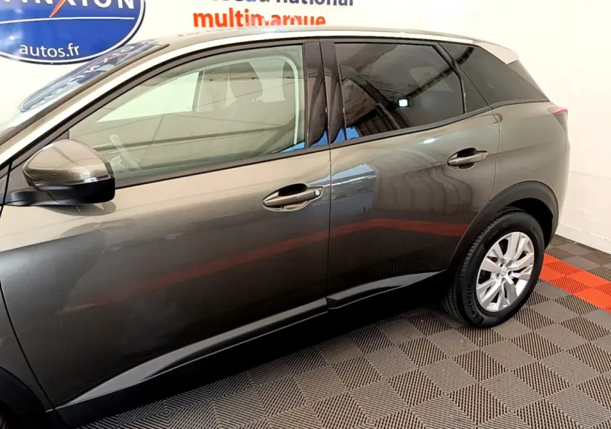 Vue latérale côté gauche d'un Peugeot 3008 gris foncé garé en intérieur avec jantes argentées visibles.