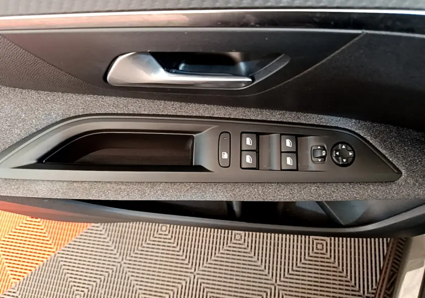 Commande des vitres et rétroviseurs sur la porte intérieure côté conducteur du Peugeot 3008 gris foncé, finition tissu.