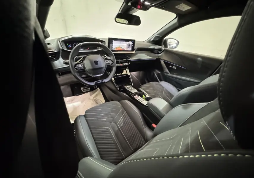 Intérieur de la Peugeot 208 Hybrid 136 eDCS6 GT vu côté conducteur, sièges noirs et tableau de bord numérique.
