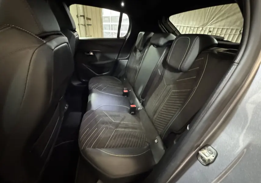 Vue intérieure arrière droite des sièges noirs avec surpiqûres jaunes de la Peugeot 208 Hybrid 136 eDCS6 GT gris clair.