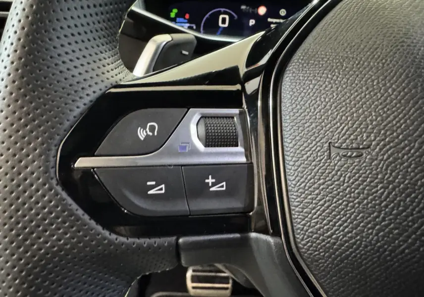 Gros plan sur les commandes gauche du volant en cuir perforé de la Peugeot 208 Hybrid 136 eDCS6 GT 2025.