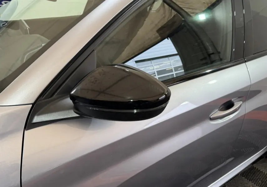 Gros plan sur le rétroviseur noir côté conducteur d'une Peugeot 208 Hybrid gris clair, vue latérale gauche.