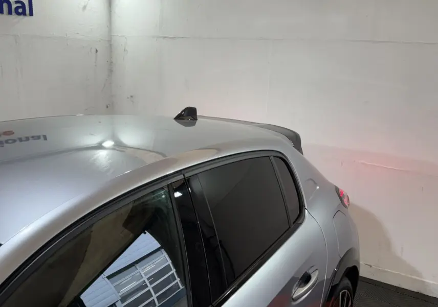 Vue 3/4 arrière droite d'une Peugeot 208 Hybrid 136 GT gris clair avec vitres teintées et antenne requin.