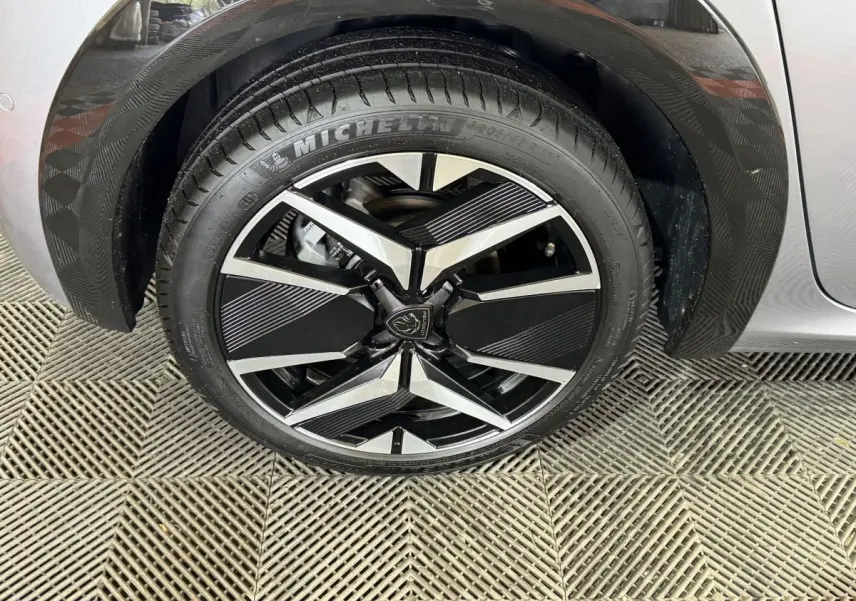 Gros plan sur la roue avant droite de la Peugeot 208 Hybrid 136 eDCS6 GT gris clair avec jante alliage noire et argent.