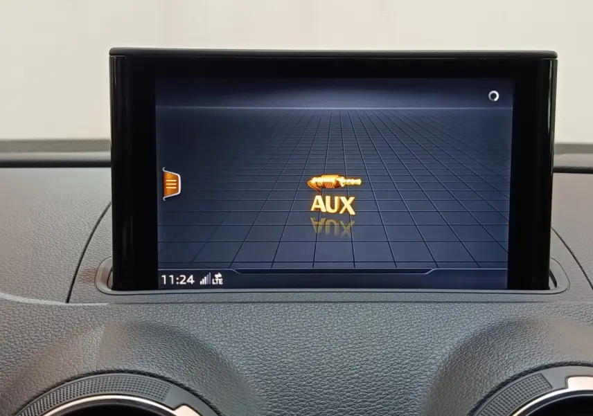 Écran tactile central affichant la connexion AUX sur le tableau de bord d'une Audi A3 blanche, vue intérieure frontale.