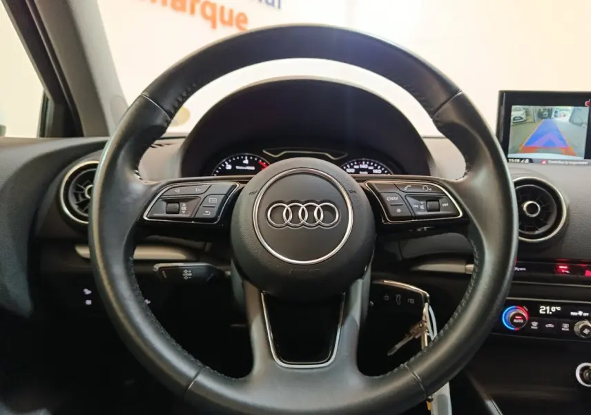 Vue rapprochée du volant cuir multifonctions noir de l'Audi A3 35 TDI 150 S tronic Business Line 2020, avec tableau de bord et écran tactile.