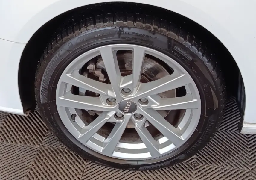 Gros plan sur la roue avant droite d'une Audi A3 blanche, jante alliage à plusieurs branches fines.
