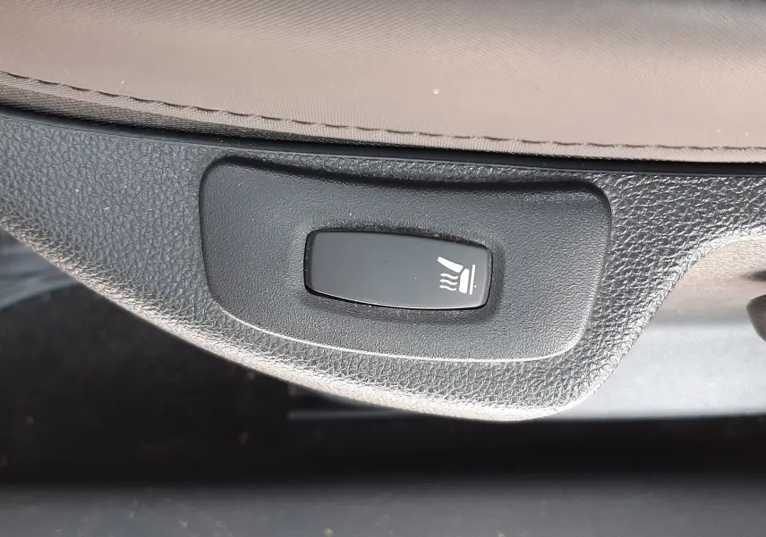 Bouton de réglage de siège chauffant sur la partie inférieure d'un siège gris cassiopée du Renault Captur 2016.