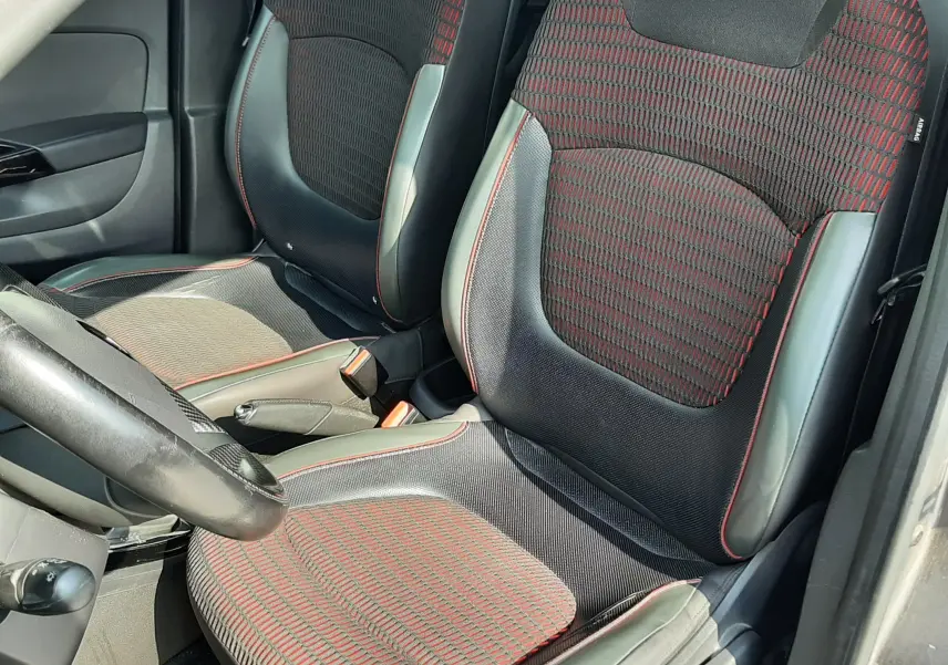 Vue intérieure côté conducteur du Renault Captur 2016, sièges tissu noir avec motifs rouges et surpiqûres rouges.