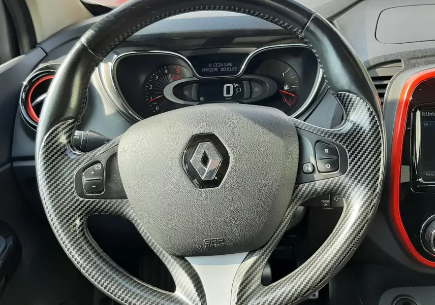 Vue rapprochée du volant en carbone d’un Renault Captur 2016 avec tableau de bord digital et habillage noir et rouge.