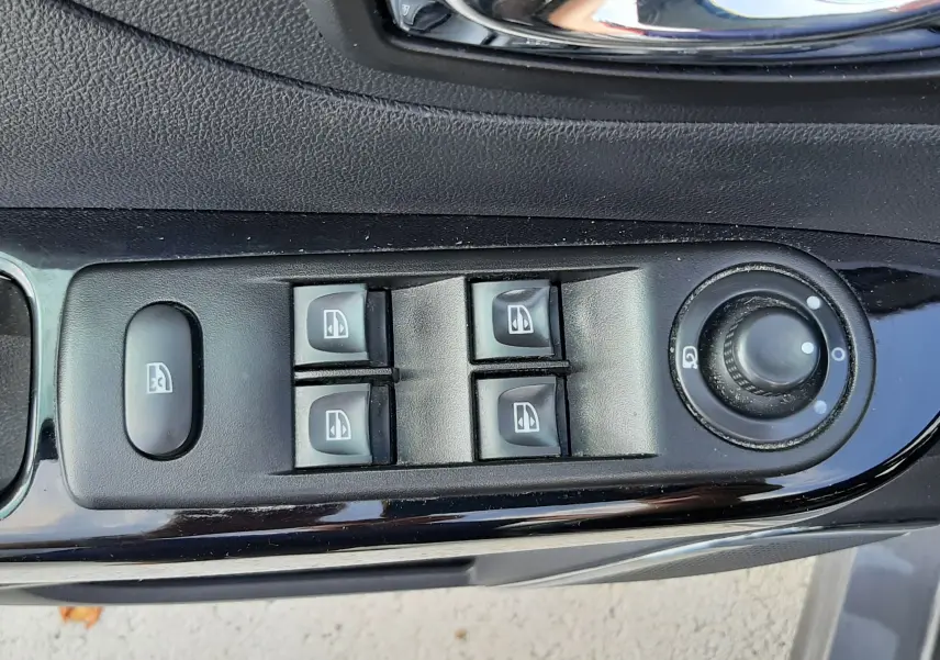 Gros plan sur les commandes de lève-vitres et réglage des rétroviseurs côté conducteur d'une Renault Captur gris cassiopée toit noir.