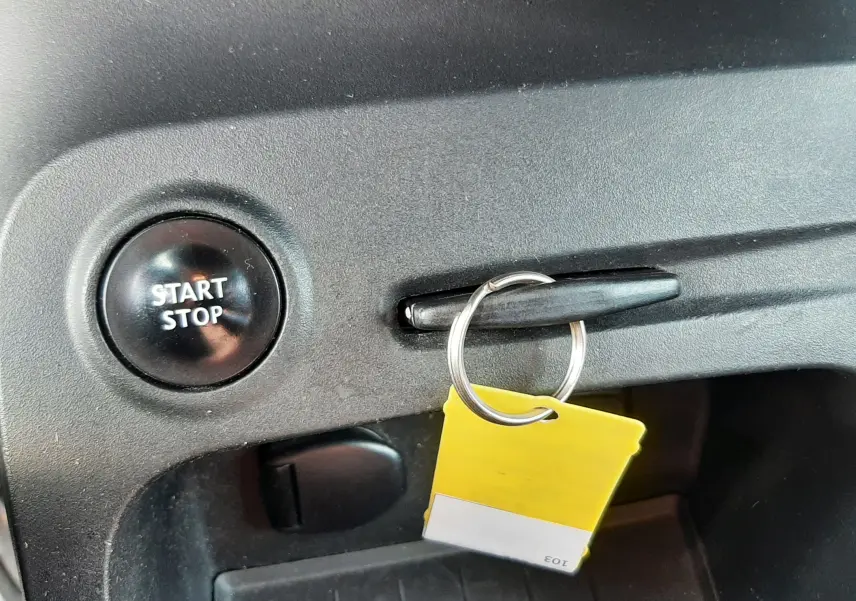 Gros plan sur le bouton Start/Stop et la clé avec porte-clés jaune dans l’habitacle du Renault Captur gris cassiopée toit noir.