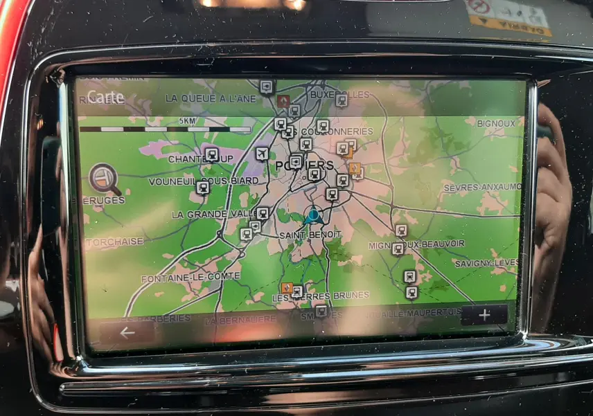 Vue rapprochée de l’écran tactile du GPS intégré dans le tableau de bord rouge et noir du Renault Captur.