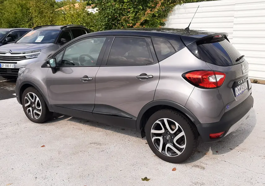 Vue 3/4 arrière droite d'un Renault Captur gris Cassiopée avec toit noir, jantes alliage et feux arrière visibles.