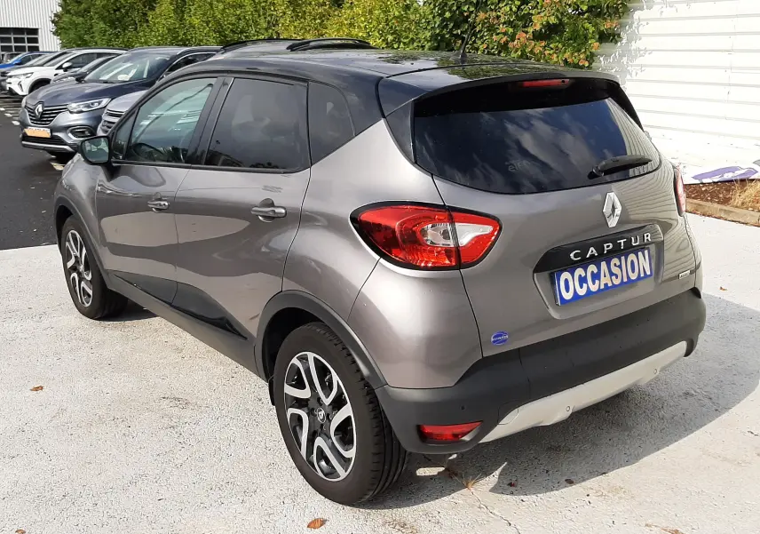 Vue 3/4 arrière droite d'un Renault Captur gris Cassiopée avec toit noir, jantes alliage et vitres teintées.