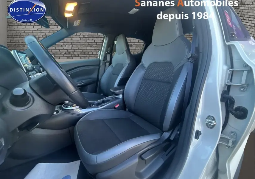 Vue intérieure côté conducteur du Nissan Juke blanc 2024, montrant les sièges avant en tissu et cuir noir.