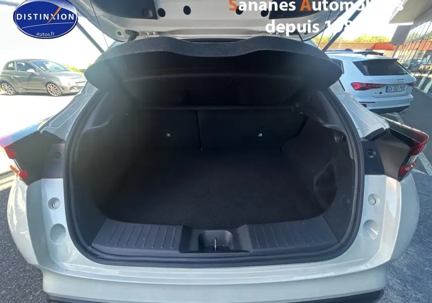Coffre ouvert vu de l'arrière d'un Nissan Juke blanc 2024 avec hayon et intérieur de coffre spacieux.