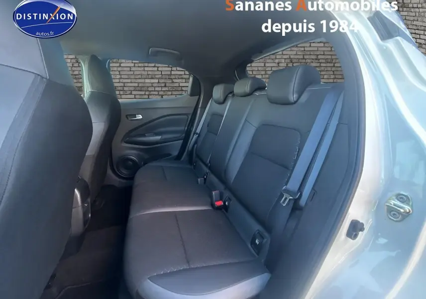 Vue côté droit de l’habitacle arrière du Nissan Juke blanc, montrant la banquette noire et la portière ouverte.