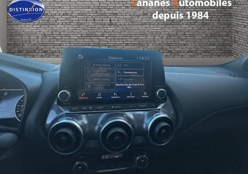 Vue intérieure du tableau de bord du Nissan Juke 2024 avec écran tactile central et commandes de climatisation circulaires.