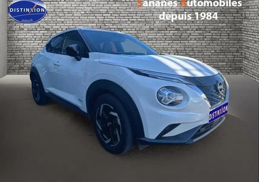 Nissan Juke blanc en 3/4 avant droit, avec coques de rétroviseurs noires et jantes au design moderne.