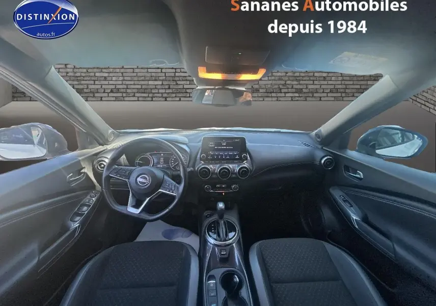 Vue intérieure avant du Nissan Juke 2024 blanc, avec tableau de bord moderne et écran tactile central.