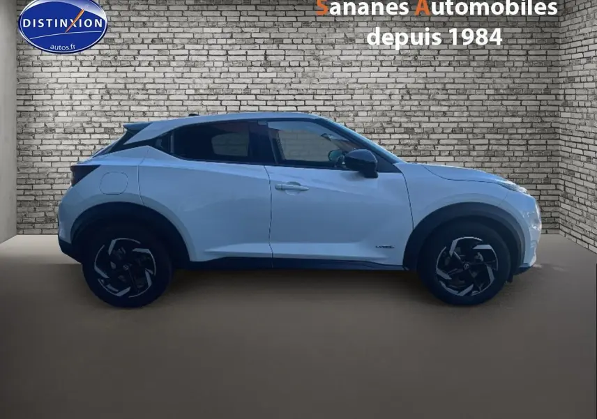 Vue de profil côté gauche du Nissan Juke blanc 2024 avec coques de rétroviseurs noires et vitres teintées.