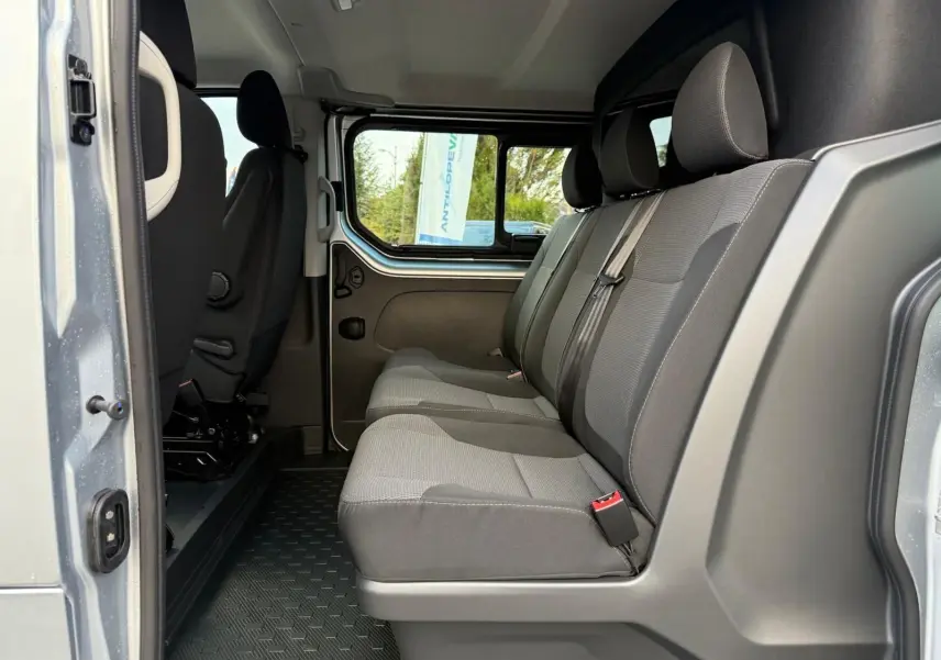 Renault Trafic cabine approfondie gris Highland vu en 3/4 arrière droit, portes arrière battantes et vitres latérales teintées.