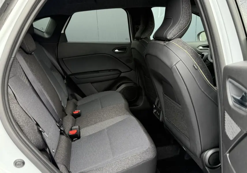 Vue intérieure côté gauche de la banquette arrière grise du Renault Captur 2025 avec sièges avant en cuir noir.