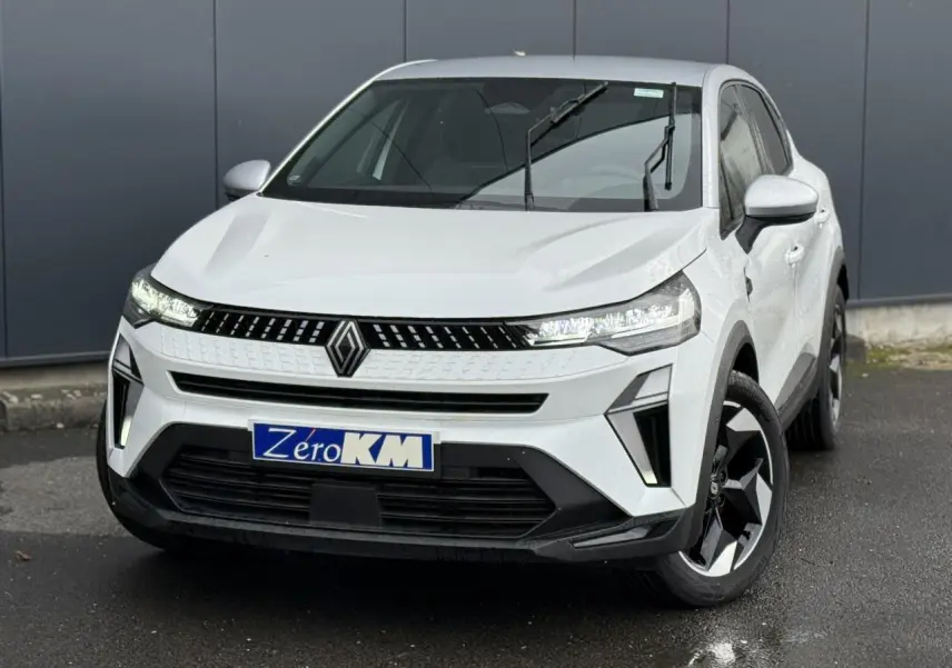 Vue 3/4 avant d’un Renault Captur blanc nacré avec toit gris Highland et jantes noires sur parking.