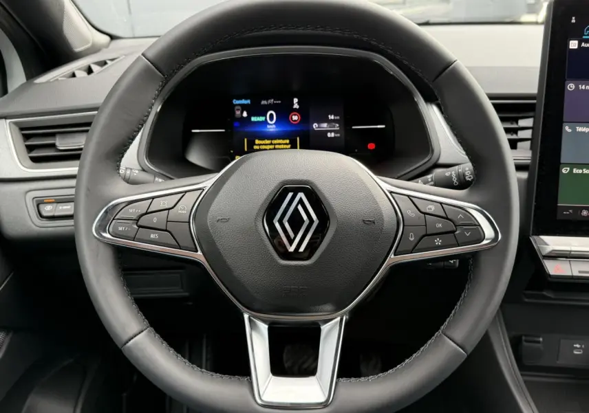 Gros plan sur le volant noir du Renault Captur 2025 avec tableau de bord numérique et écran tactile latéral visible.