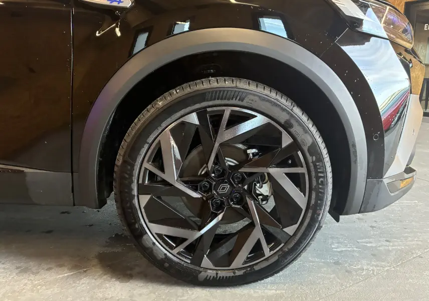 Gros plan sur la roue avant droite du Renault Captur noir étoile avec jante diamantée et badge Esprit Alpine bleu.