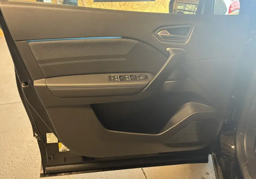 Porte intérieure côté gauche du Renault Captur E-Tech hybride 2025 en noir étoile métal avec surpiqûres blanches.