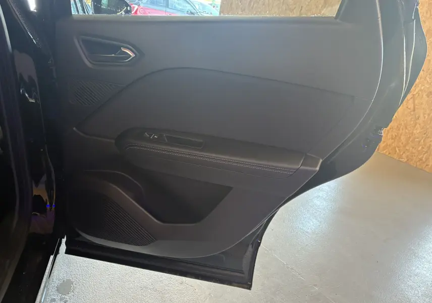 Porte arrière droite ouverte du Renault Captur noir étoile métal avec intérieur noir et surpiqûres blanches.