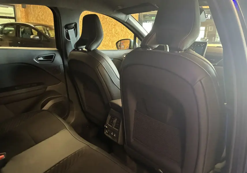 Vue intérieure arrière du Renault Captur 2025, sièges en cuir noir et console centrale avec aérateurs et ports USB.