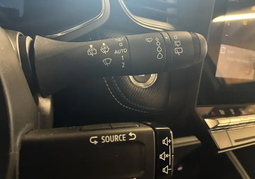 Gros plan sur la commande des essuie-glaces et du régulateur audio dans l'habitacle noir du Renault Captur E-Tech 2025.