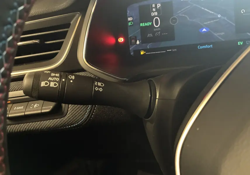 Gros plan sur la commande des phares et clignotants à gauche du volant dans le tableau de bord du Renault Captur hybride 2025.